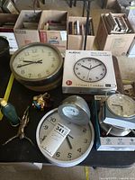 Group shot showing multiple clocks, boxed Auriol clock, figurines and Sharp alarm clock packaging