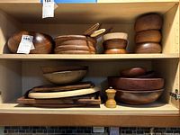 Entire lot on two cabinet shelves showing variety of bowls, boards, spatulas, pepper mill