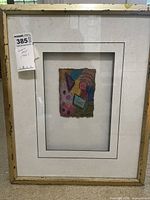 Front view of framed artwork showing gold frame, mat, and art