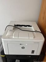 Front and top view of HP LaserJet Pro M203dw printer showing HP logo and included power cable