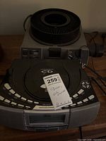 Kodak Ektagraphic III AMT projector with slide tray stacked beneath Wedge CD clock radio, showing fronts and cords