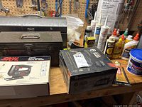 Overall lot view showing jigsaw box, battery charger box, metal toolbox and adhesives