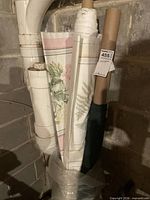 Group of three fabric bolts on cardboard cores showing floral stripe, fern botanical, and solid dark green fabrics