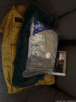 Overall lot showing yellow puffer, green throw, vacuum bag of towels, wrapped picture