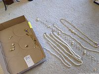 Overview showing pearl necklaces, gold-tone chain with purple cabochon and pearl beads, earrings and bracelet inside box