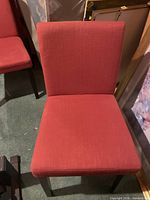 Front view of red upholstered dining chair with black legs