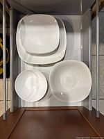 Drawer view showing stacked white porcelain square plates and bowls