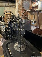 Full view of metal table lamp showing three arms, base, and finial