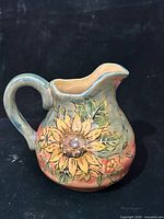 Front view of ceramic pitcher showing sunflower design and curved spout.
