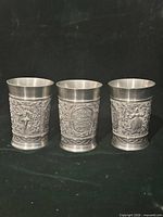 Front view of all three pewter cups showing relief designs