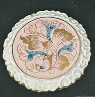 Front view showing pink center, white rim, gilt and teal floral design
