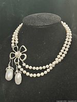 full view of necklace on bust with earrings attached, shows overall design and pearl colour