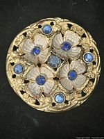 Front view showing floral enamel design and blue stones