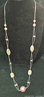 Full view of long layered necklace hanging on display form