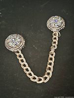 Front view showing both round rhinestone clips and connecting chain