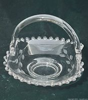 Front view of clear pressed glass basket displaying beaded rim and etched floral design