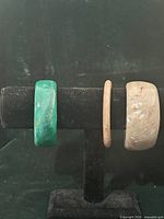 Three bangles on display stand: green wide, beige slim, beige wide
