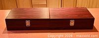 Two closed wood grain veneer boxes side by side showing latches