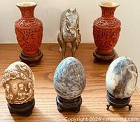 Full lot view showing two red vases, metal horse, three stone eggs on stands