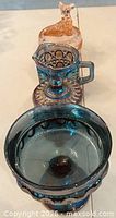 Four assorted coloured glass pieces lined from largest bowl to smallest animal dish