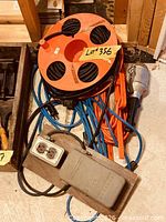 Group of extension cord reel, loose cords, work light and outlet box