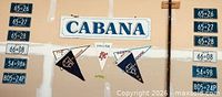 Full display of 12 licence plates, Cabana sign and pennants mounted on wall