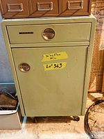 Front view of cabinet with drawer and door closed showing handles and brand badge