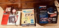 All five items grouped: Simoniz polisher case, Jobmate stapler box, EZ Moves kit box, mini vise box, jar of fasteners