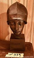 Front view showing facial features, helmet, base inscription
