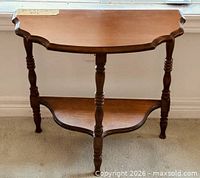 Front view of demi-lune console table showing scalloped top and turned legs