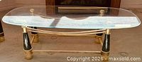 Full view of glass coffee table showing brass, black, and faux tusk frame