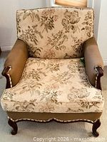 Front view of upholstered armchair showing floral fabric and wood frame
