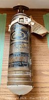 Full view of brass Pyrene fire extinguisher showing label and bracket