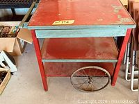Top view of three-tier red and green metal cart showing shelves and handle