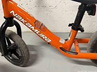 Left side view showing orange frame, Nakamura logo, front black fork and wheel