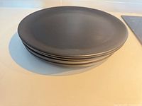 Stack of four dark gray dinner plates side view