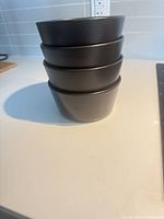 Stack of four dark gray ceramic bowls, side profile