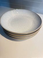 Stack of four white speckled bowls showing interior glaze and gold rim