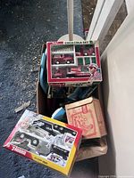 Overview of lot showing Coca-Cola set, NASA set and other boxed items in bin