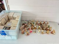 Plastic bin of patterned Cherished Teddies boxes beside array of figurines on table
