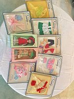 Group shot of boxed doll and ten blister-card outfits on table