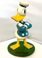 Front view of Donald Duck figure showing crossed arms pose and base