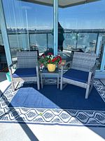 Full view of two chairs, side table, and rug on balcony