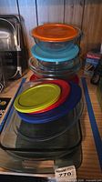 Stacked glass bakeware with assorted lids visible