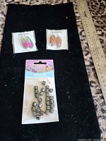 Full lot with two pairs of earrings on cards and packaged malachite beads alongside ruler