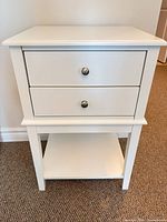 Front view showing two drawers with brushed nickel knobs and lower shelf