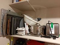 Shelf showing entire lot: bakeware, pot, colander, toaster, knives