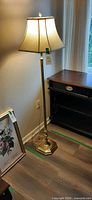 Full view of brass-tone floor lamp beside furniture