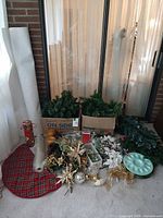 Lot overview showing garland, faux snow roll, tree skirt, crafting picks, ribbon, tray