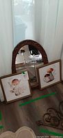Group shot of two framed mushroom prints and oval mirror leaning against curtain
